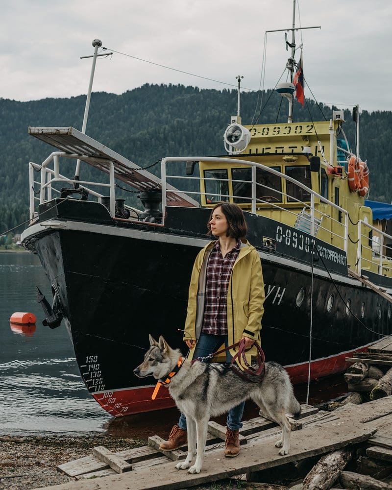 Woman with dog near a boat, showcasing the mix of life.